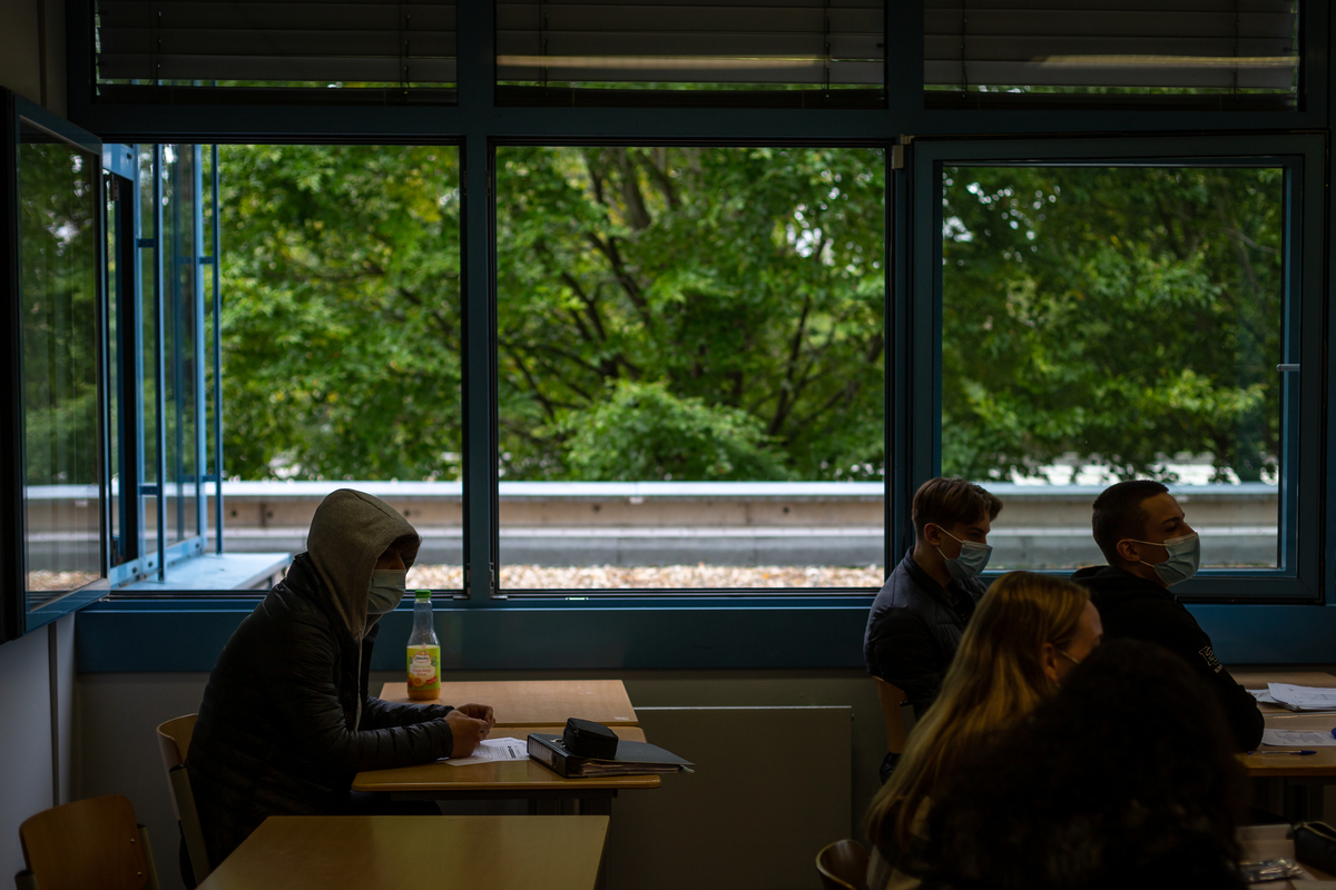 Students sit in a classroom with masks on and the windows wide up at a high school in Brühl, Germany, near Cologne. Image by Ryan Delaney. Germany, 2020. Students sit in a classroom with masks on and the windows wide up at a high school in Brühl, Germany, near Cologne. Image by Ryan Delaney. Germany, 2020.
