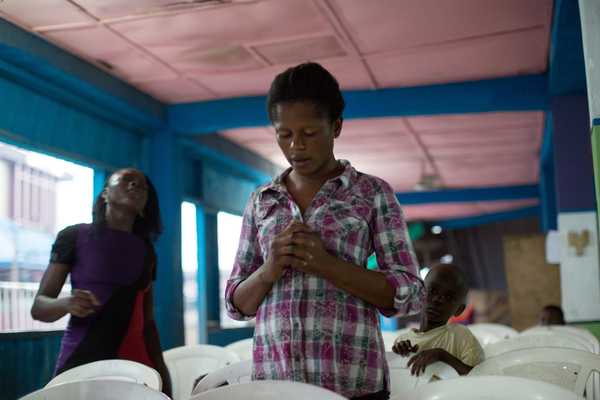 Bunmi Aiyenuro, 23, prays during a Wednesday evening service at Christ Embassy church in the Badia neighborhood of Lagos. Bunmi says she has had seven abortions and has never been educated about birth control. After two subsequent miscarriages, her boyfriend, who was finally ready for a child, left her for her best friend. Image by Allison Shelley. Nigeria, 2013. Media file: aj_badia_005.jpg