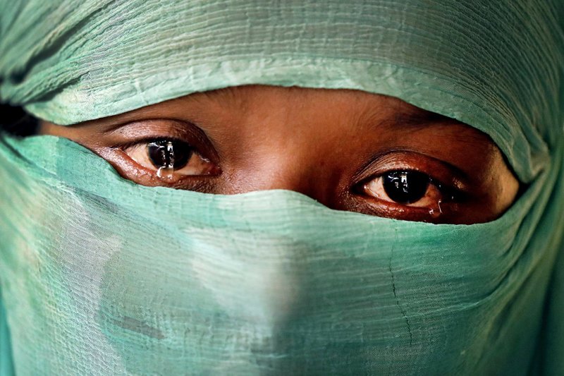 In this Wednesday, Nov. 22, 2017, photo, F, 22, who says she was raped by members of Myanmar’s armed forces in June and again in September, cries as she speaks to The Associated Press in her tent in Kutupalong refugee camp in Bangladesh. The Associated Press has found that the rape of Rohingya women by Myanmar’s security forces has been sweeping and methodical. The AP interviewed 29 women and girls who say they were raped by Myanmar’s armed forces, and found distinct patterns in their accounts, their assailants’ uniforms and the details of the rapes themselves. The most common attack involved groups of soldiers storming into a house, beating any children inside and then beating and gang raping the women. Image by Wong Maye-E. Bangladesh, 2017. In this Wednesday, Nov. 22, 2017, photo, F, 22, who says she was raped by members of Myanmar’s armed forces in June and again in September, cries as she speaks to The Associated Press in her tent in Kutupalong refugee camp in Bangladesh. The Associated Press has found that the rape of Rohingya women by Myanmar’s security forces has been sweeping and methodical. The AP interviewed 29 women and girls who say they were raped by Myanmar’s armed forces, and found distinct patterns in their accounts, their…