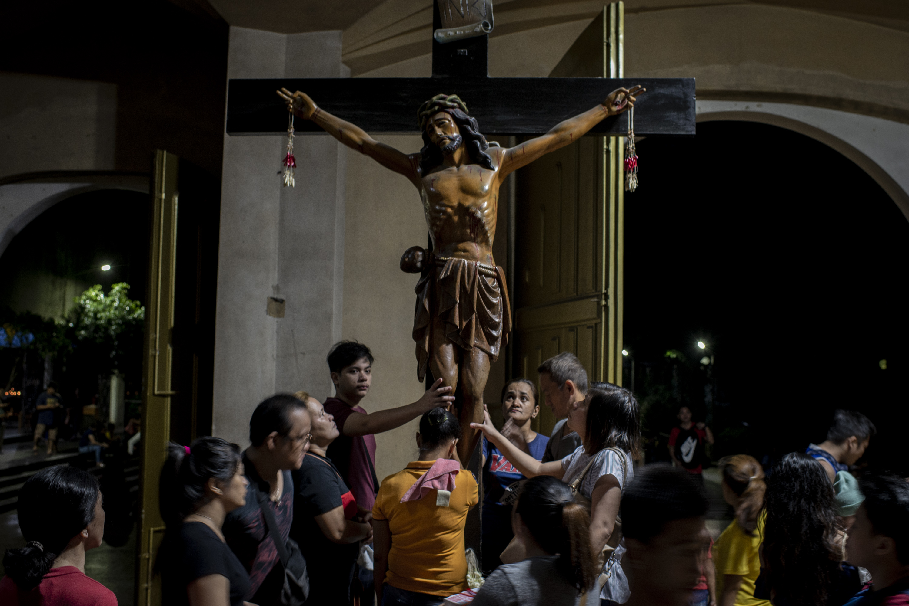 Parishioners touch the crucifix after an evening service at Baclaran Church in Manila. Image by Eloisa Lopez. Philippines, 2018. Parishioners touch the crucifix after an evening service at Baclaran Church in Manila. Image by Eloisa Lopez. Philippines, 2018.