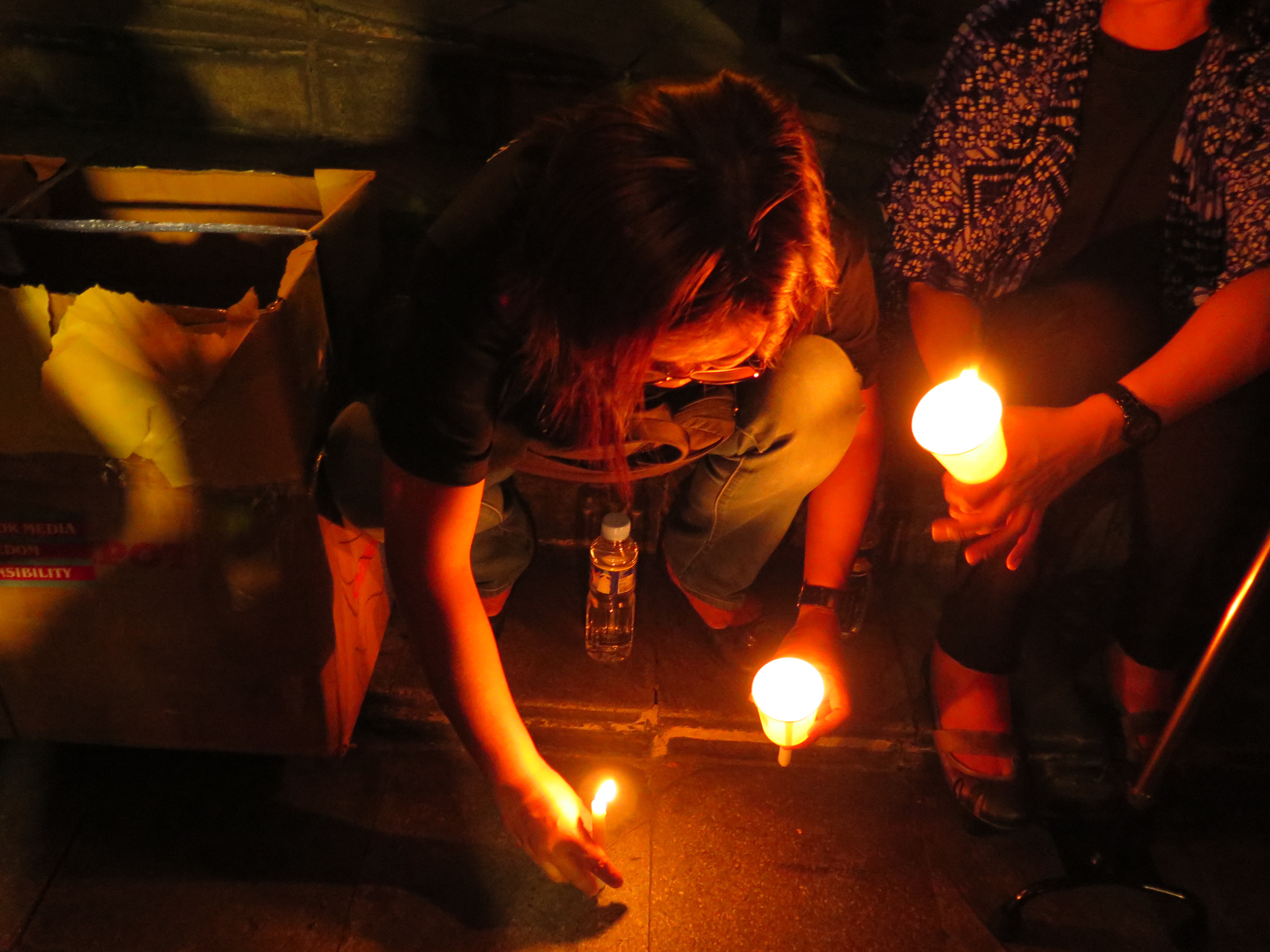 A woman lights candles in Manila to commemorate the anniversary of the Maguindanao Massacre, in which 34 journalists were murdered. In the six years that have passed since the killings, trial proceedings have stalled, and witnesses for the prosecution continue to be murdered. Image by Saul Elbein. The Philippines, 2015. Media file: img_0099.jpg