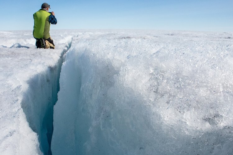 University of Montana glaciologist Joel Harper examines a deep crack in the ice sheet called a crevasse. Image by Amy Martin. Greenland, 2018. University of Montana glaciologist Joel Harper examines a deep crack in the ice sheet called a crevasse. Image by Amy Martin. Greenland, 2018.