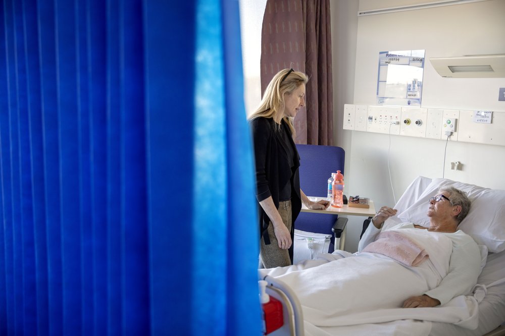 Dr. Jennifer Stevens, a pain specialist, talks with patient Cheryl Rowley who is awaiting surgery at St. Vincent's Hospital in Sydney, Australia, on July 17, 2019. "We were just pumping this stuff out into our local community, thinking that that had no consequences," says Stevens, a vocal advocate for changing opioid prescribing practices. "And now, of course, we realize that it does have huge consequences." Image by David Goldman. Australia, 2019. Dr. Jennifer Stevens, a pain specialist, talks with patient Cheryl Rowley who is awaiting surgery at St. Vincent's Hospital in Sydney, Australia, on July 17, 2019. "We were just pumping this stuff out into our local community, thinking that that had no consequences," says Stevens, a vocal advocate for changing opioid prescribing practices. "And now, of course, we realize that it does have huge consequences." Image by David Goldman. Australia, 2019.