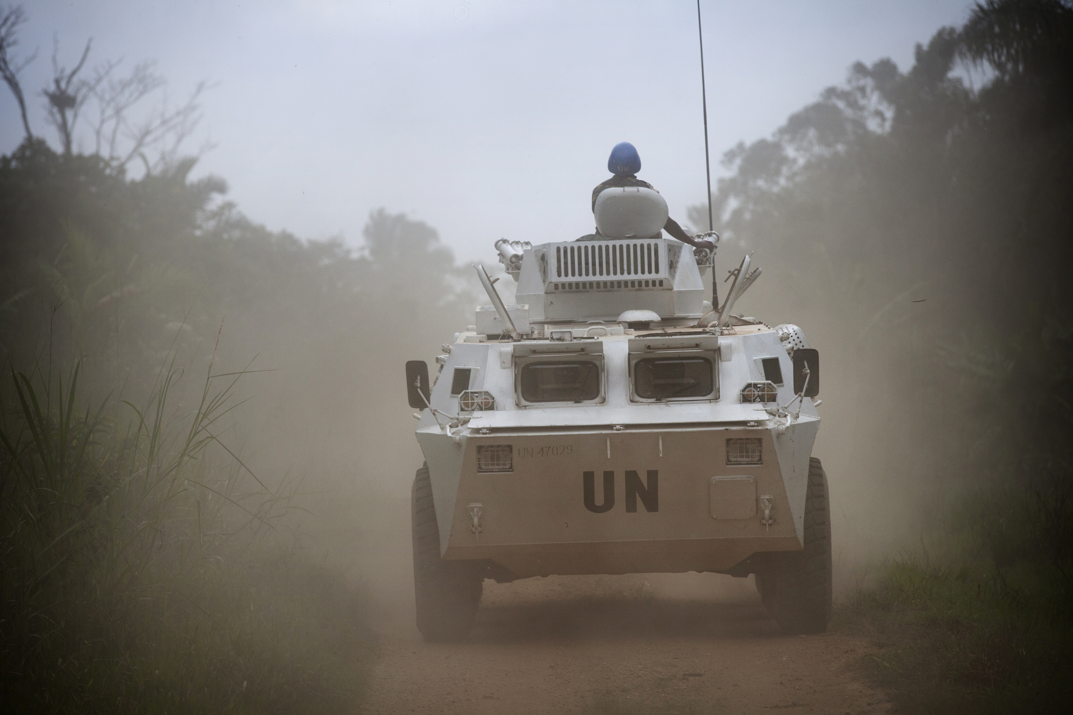 An armored UN personnel carrier on patrol drives down a road.
