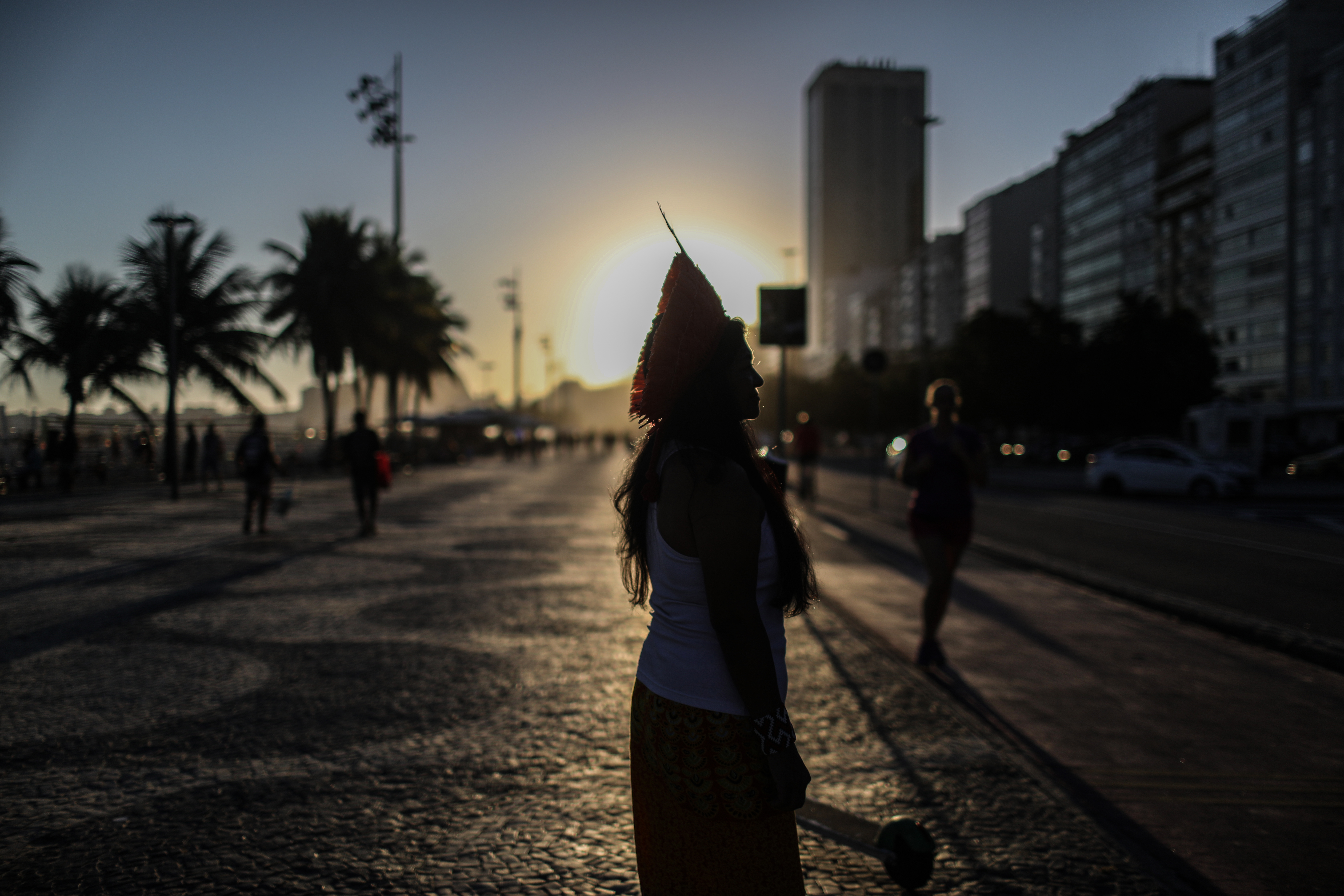 Foto_1_0.jpeg The silhouette of a woman in a headdress standing against the sun as it sets.