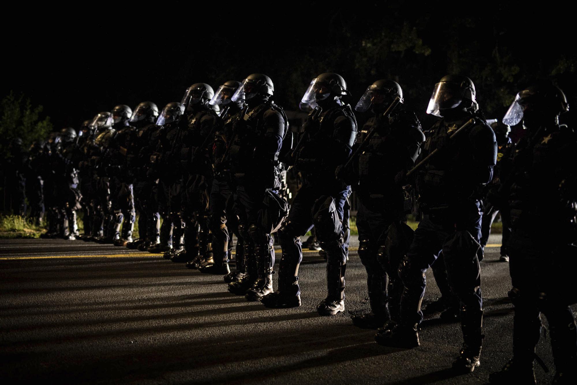 2000.jpeg Police officers in riot gear line up across a street.