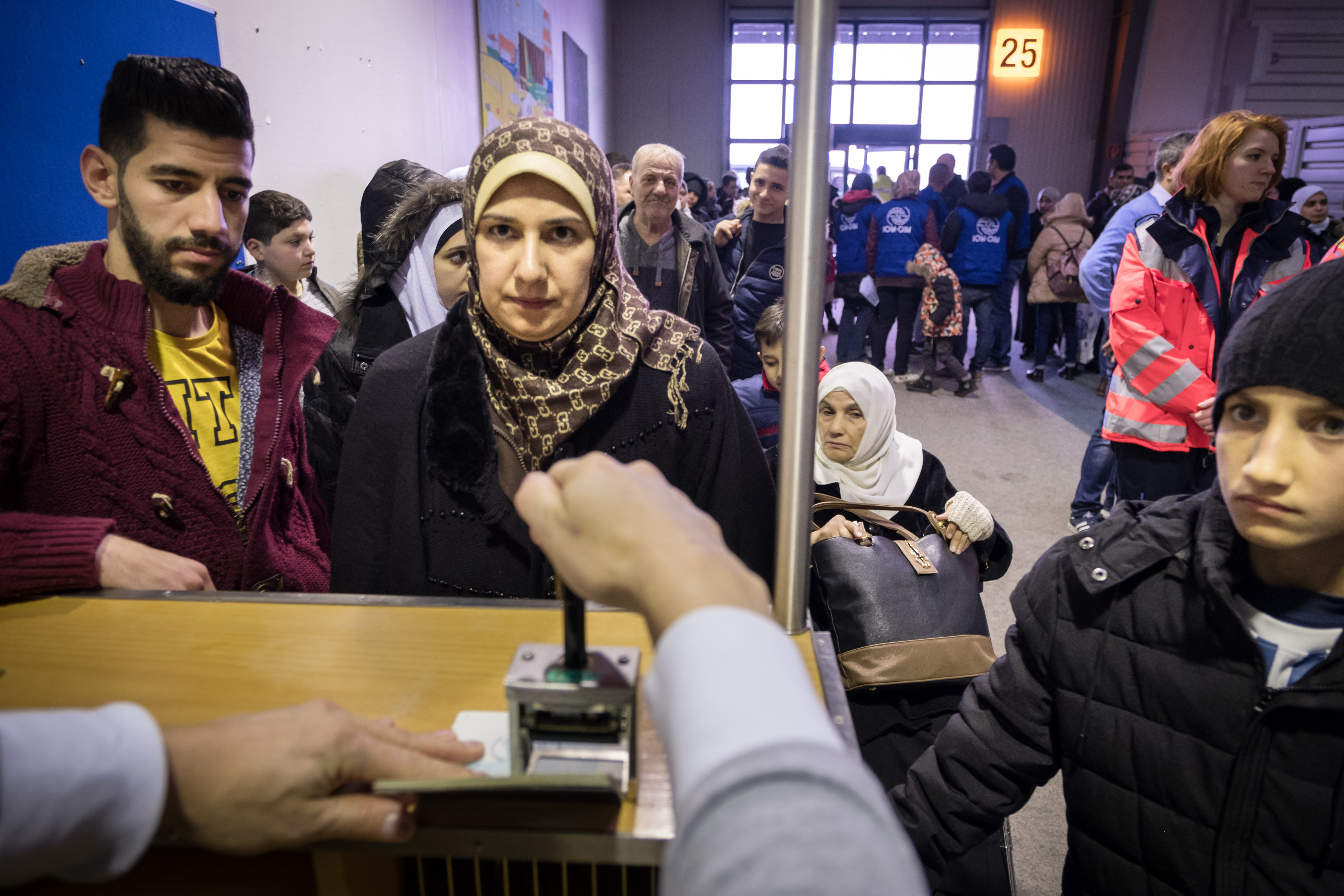 An immigration officer stamps the passports of a Syrian family who have just landed at Hanover airport