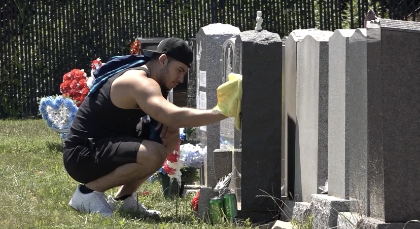 man kneeling beside headstones