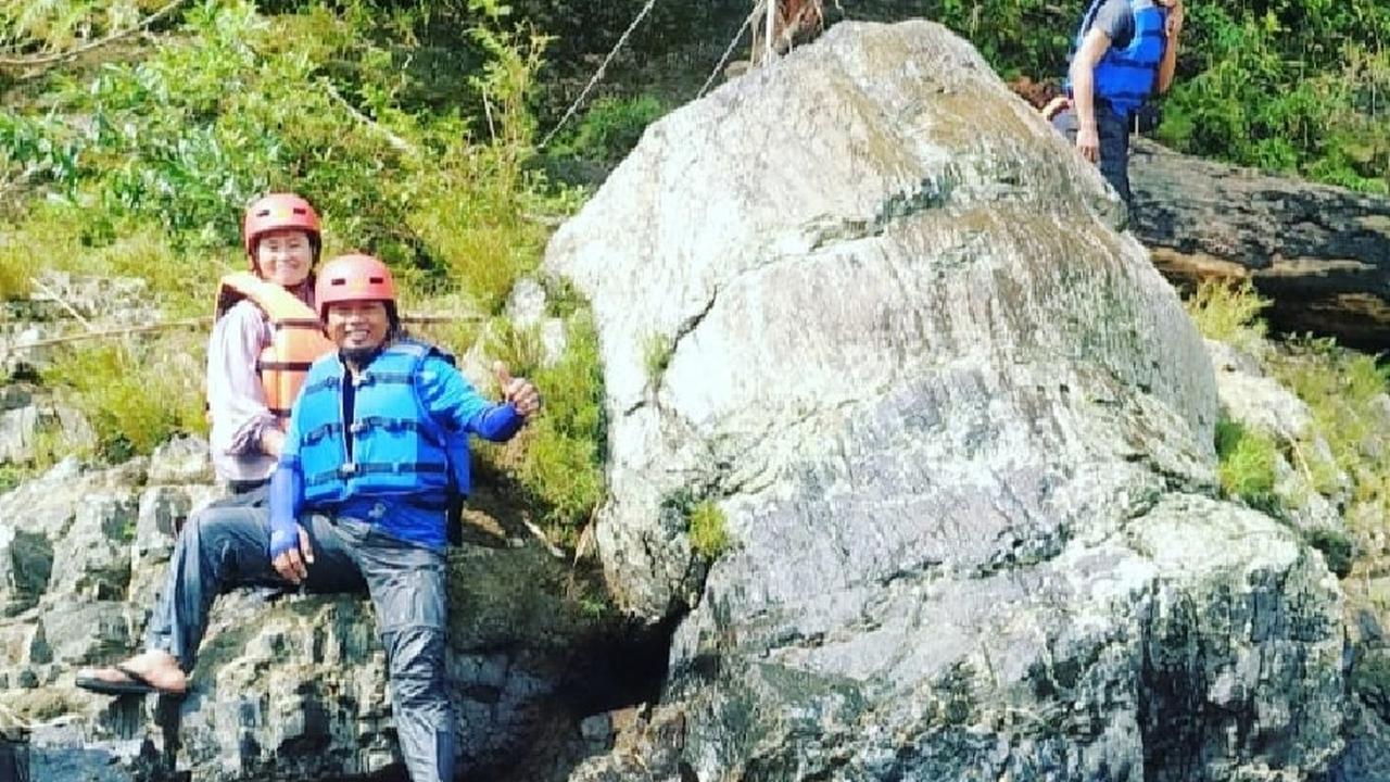 Wisatawan arung jeram saat berpose di samping fosil pohon Araucarioxylon di area Geopark Merangin di Desa Air Batu. Menurut para ahli geologi, fosil pohon ini berumur 300 juta tahun atau periode permian. (Liputan6.com/dok Air Batu River)