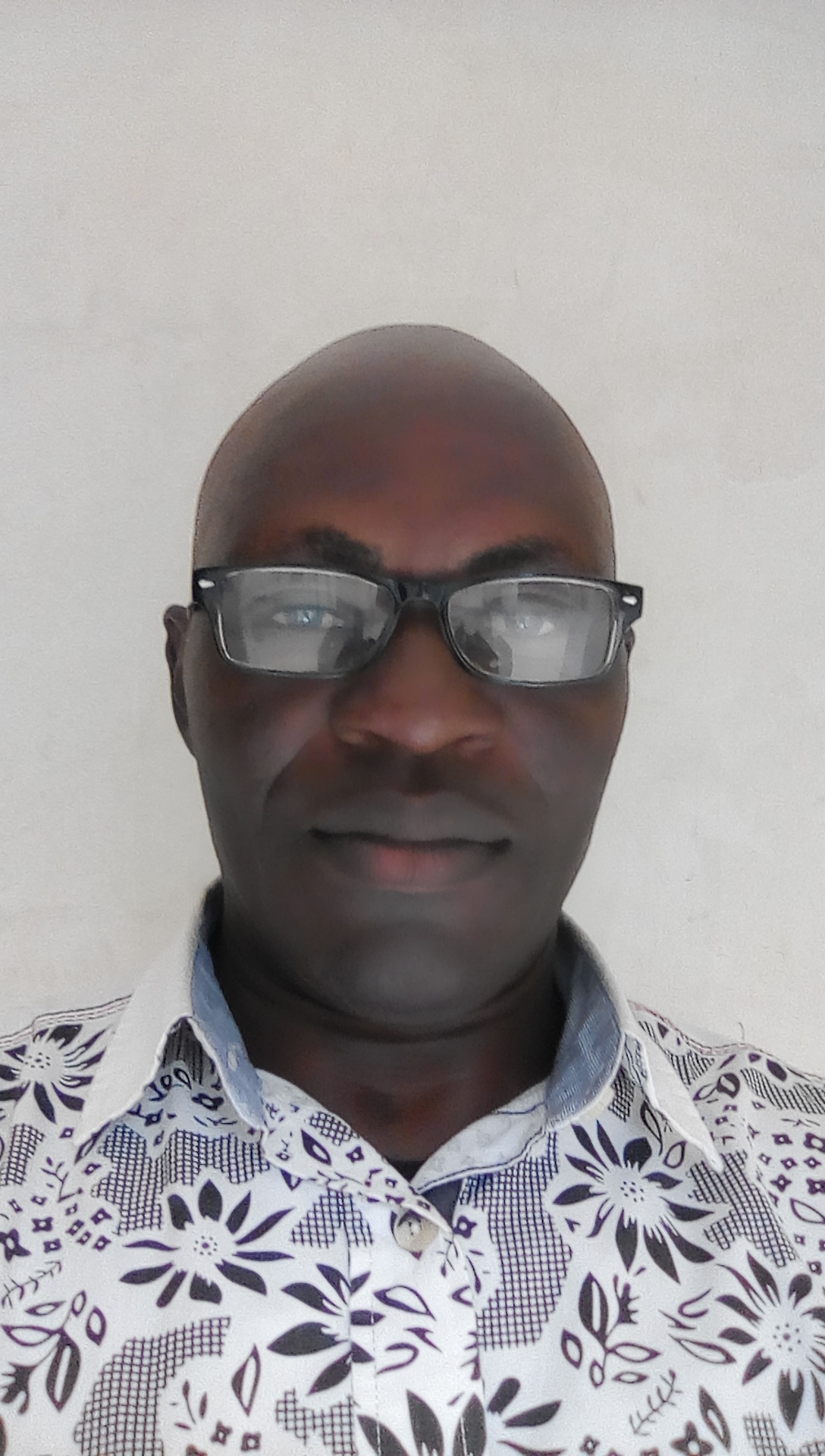 A man wears glasses and a white shirt, he smiles at the camera.