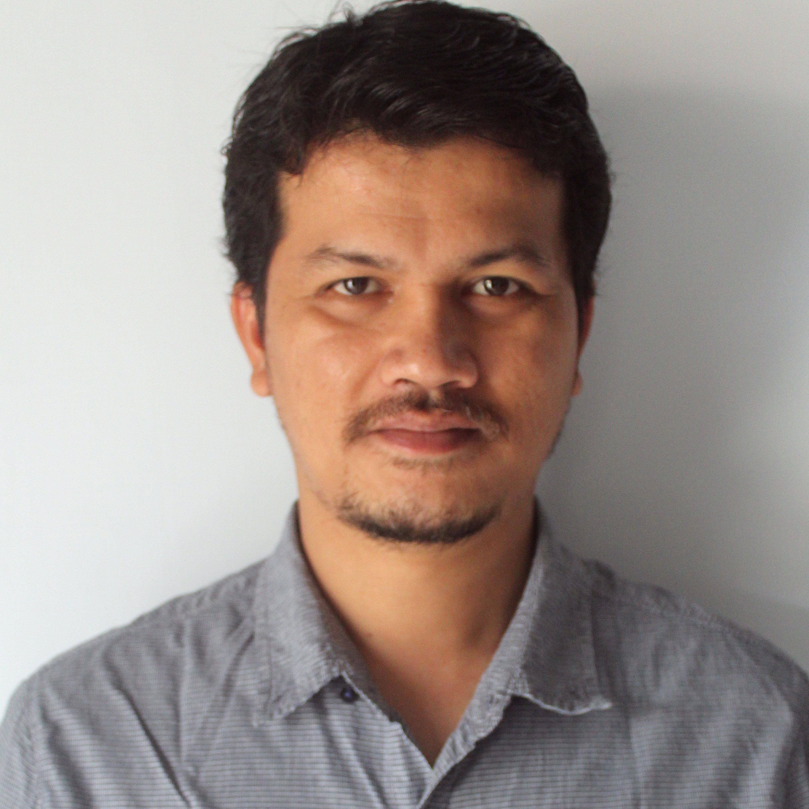 A person wears a grey shirt and has short black hair.