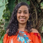 A person wears a bright red shirt with feathers.
