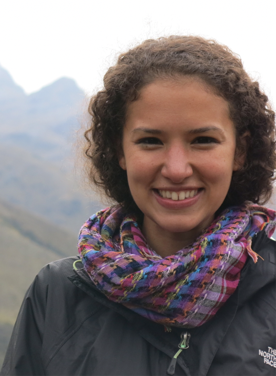 A woman with curly hair and a purple scarf stares in the camera