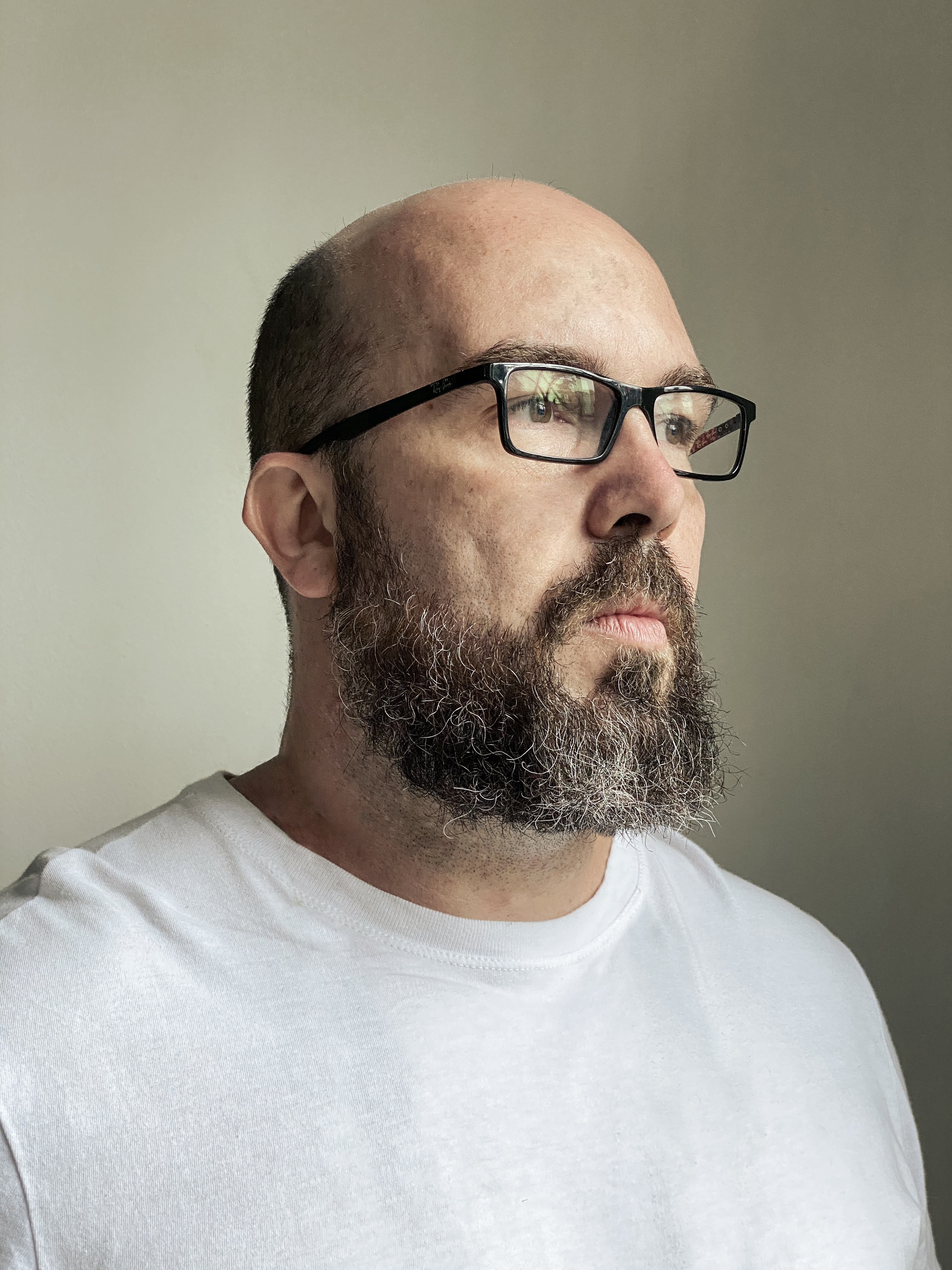 Man with a beard and black glasses looks to the left