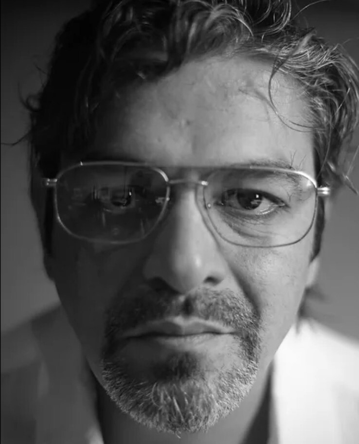 A person wears a shirt and glasses.