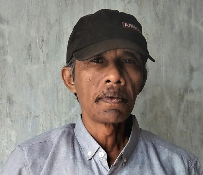 A man wears a cap and a blue shirt.