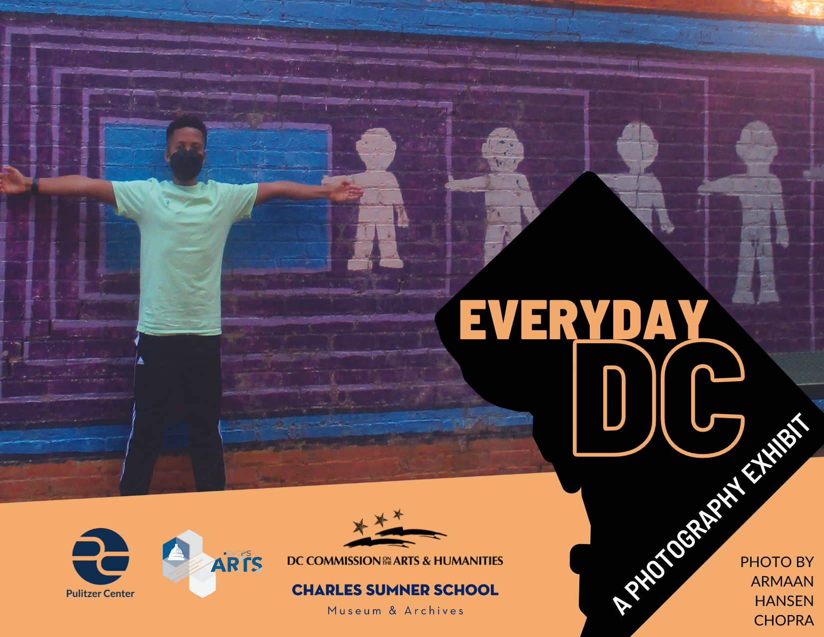 A young boy stands in front of a mural with his arms outstretched.