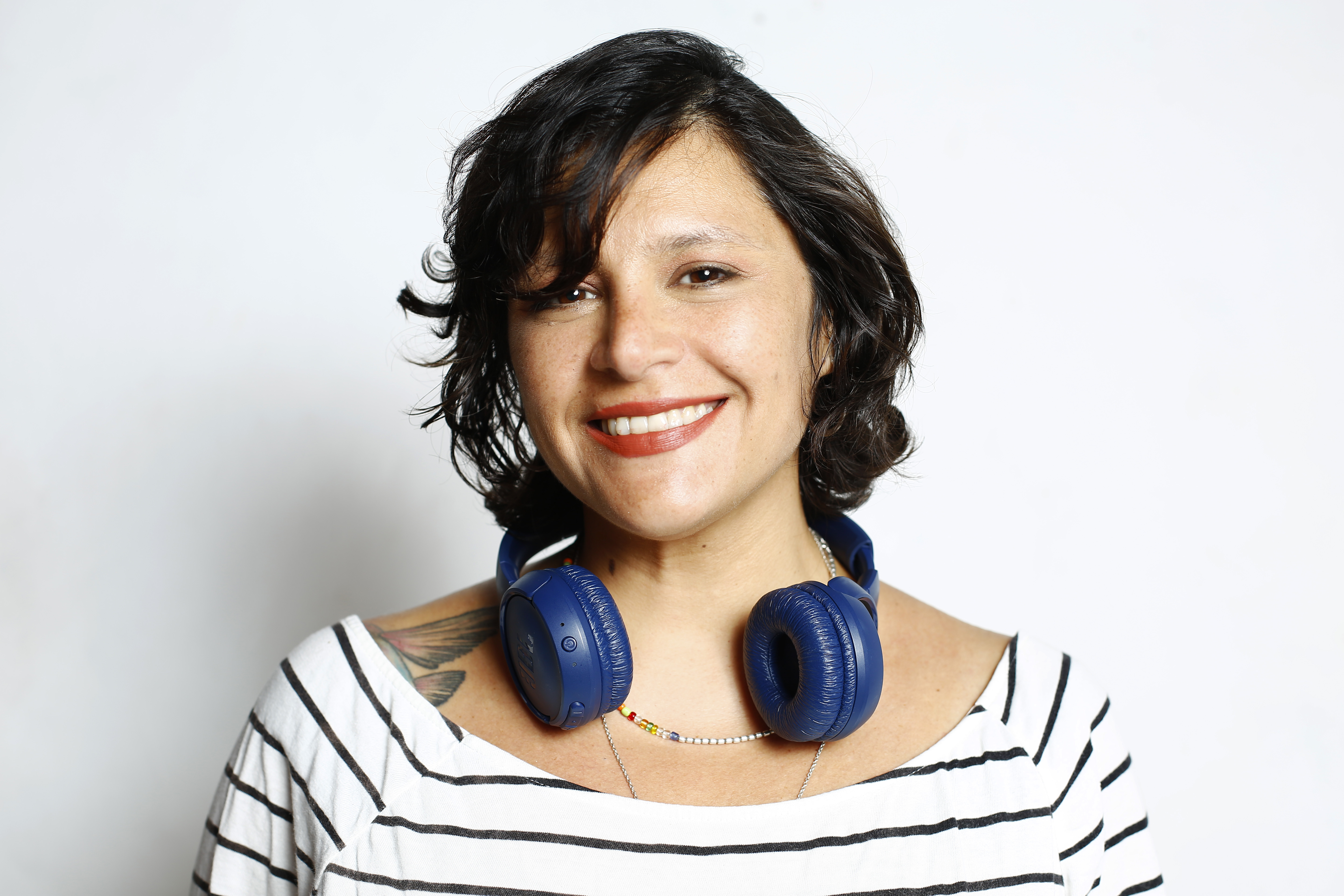 A woman with short hair, headphones, and wears a striped shirt.