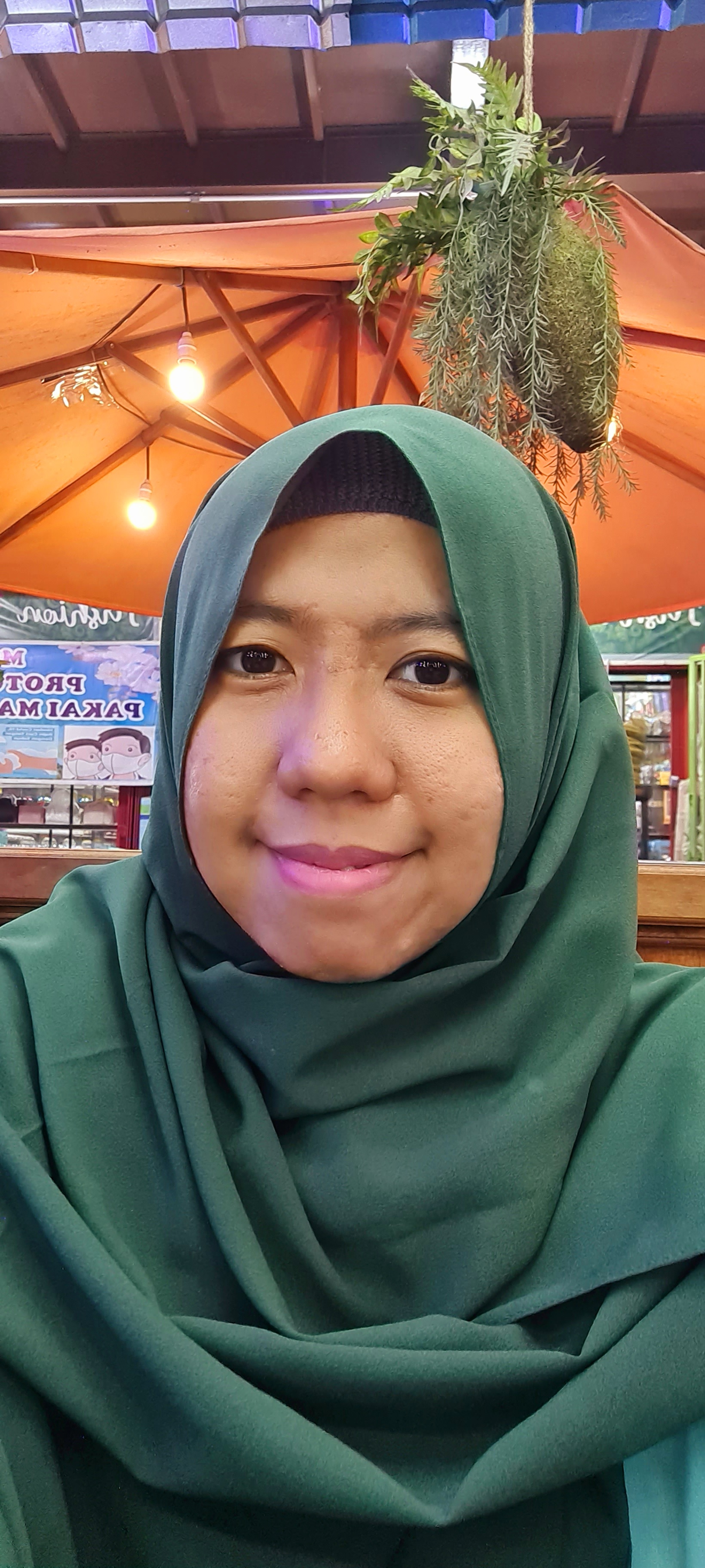 a woman with a green hijab stares into the camera
