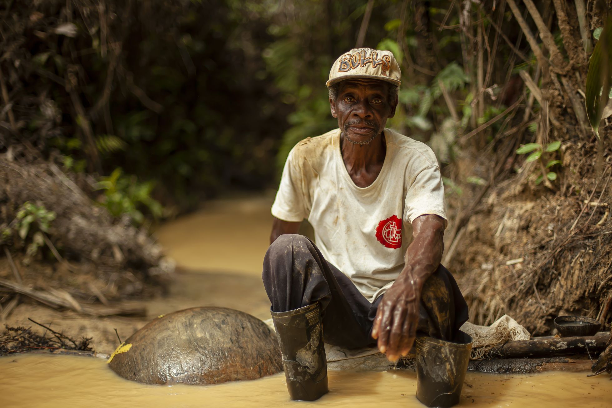 Un hombre al lado de un rio con sus herramientas para extraer oro