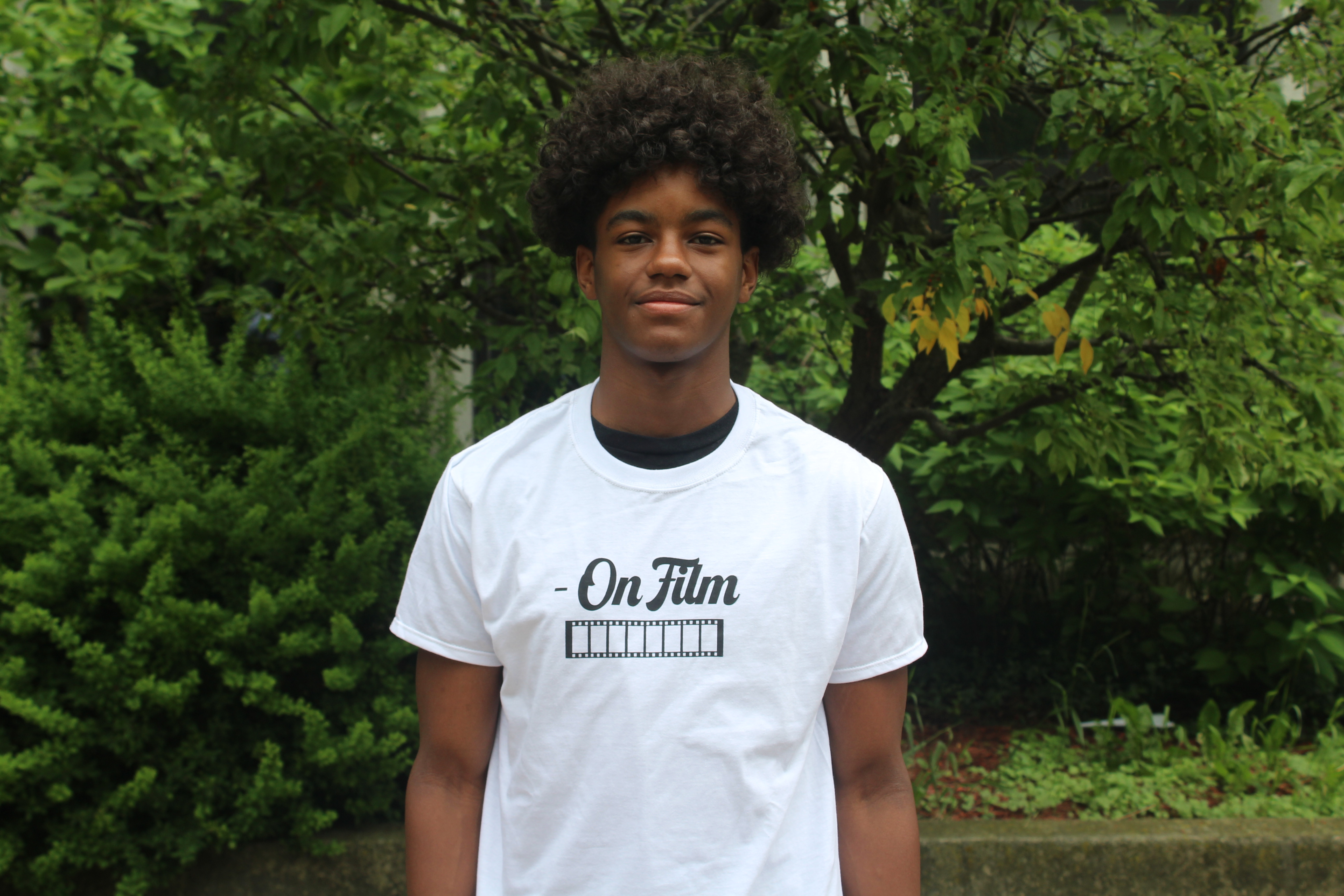 Jamar Jackson - poetry contest winner.jpg Jamar Jackson stands and smiles in a white tee shirt with trees and greenery in the background.