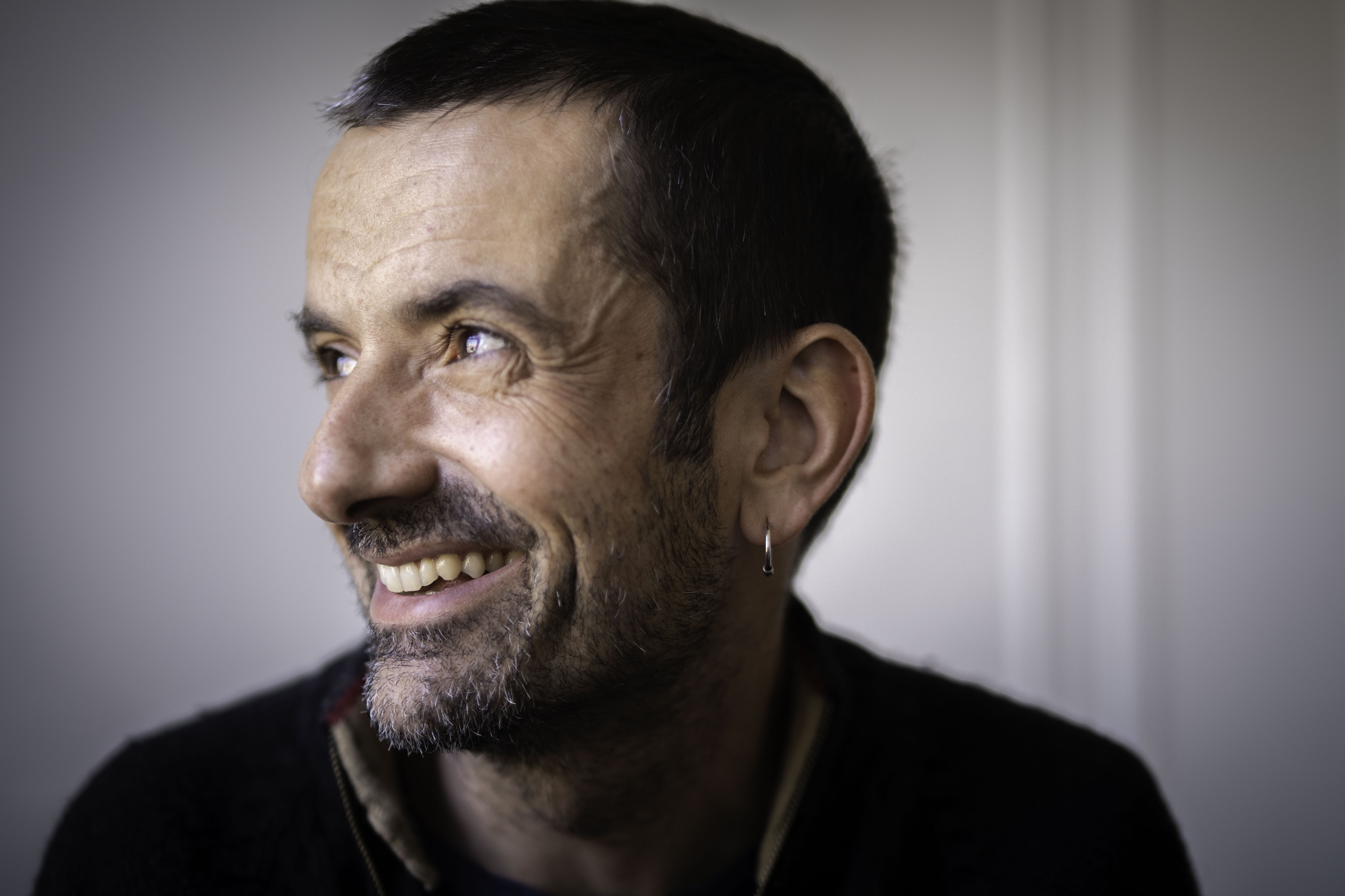 A profile headshot of a smiling man with short dark hair