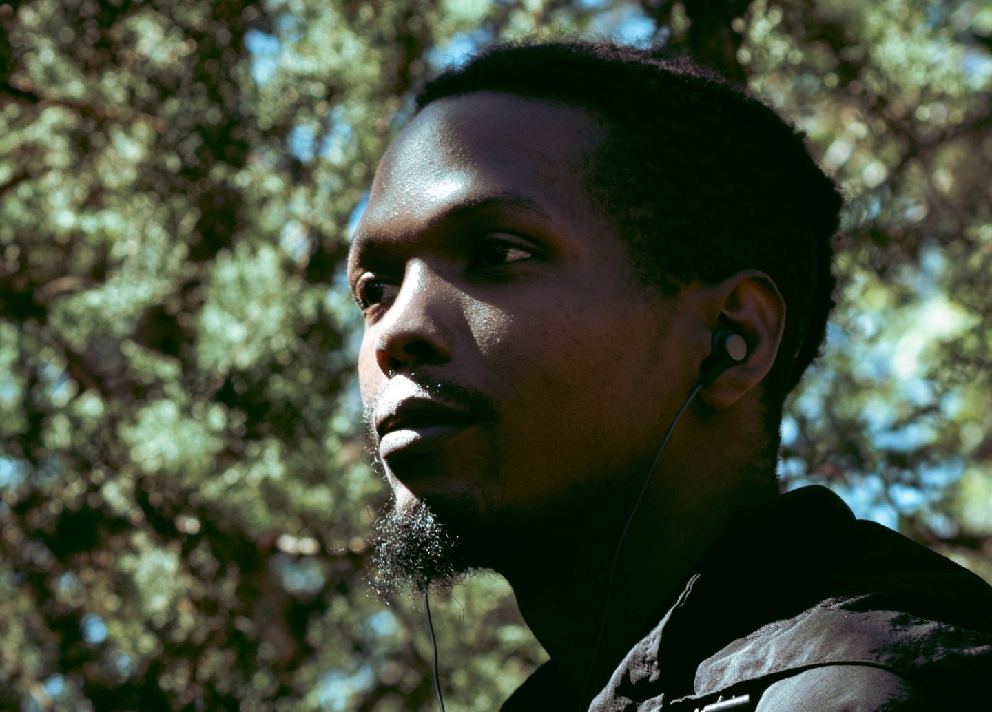A profile portrait of a man with dark skin and short dark hair