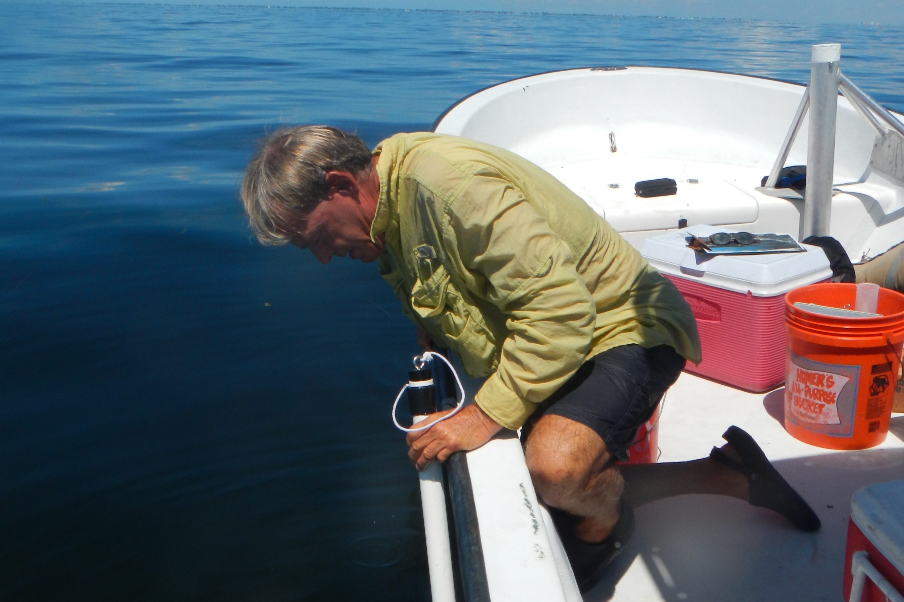 a man uses a water measurement tool off a boat