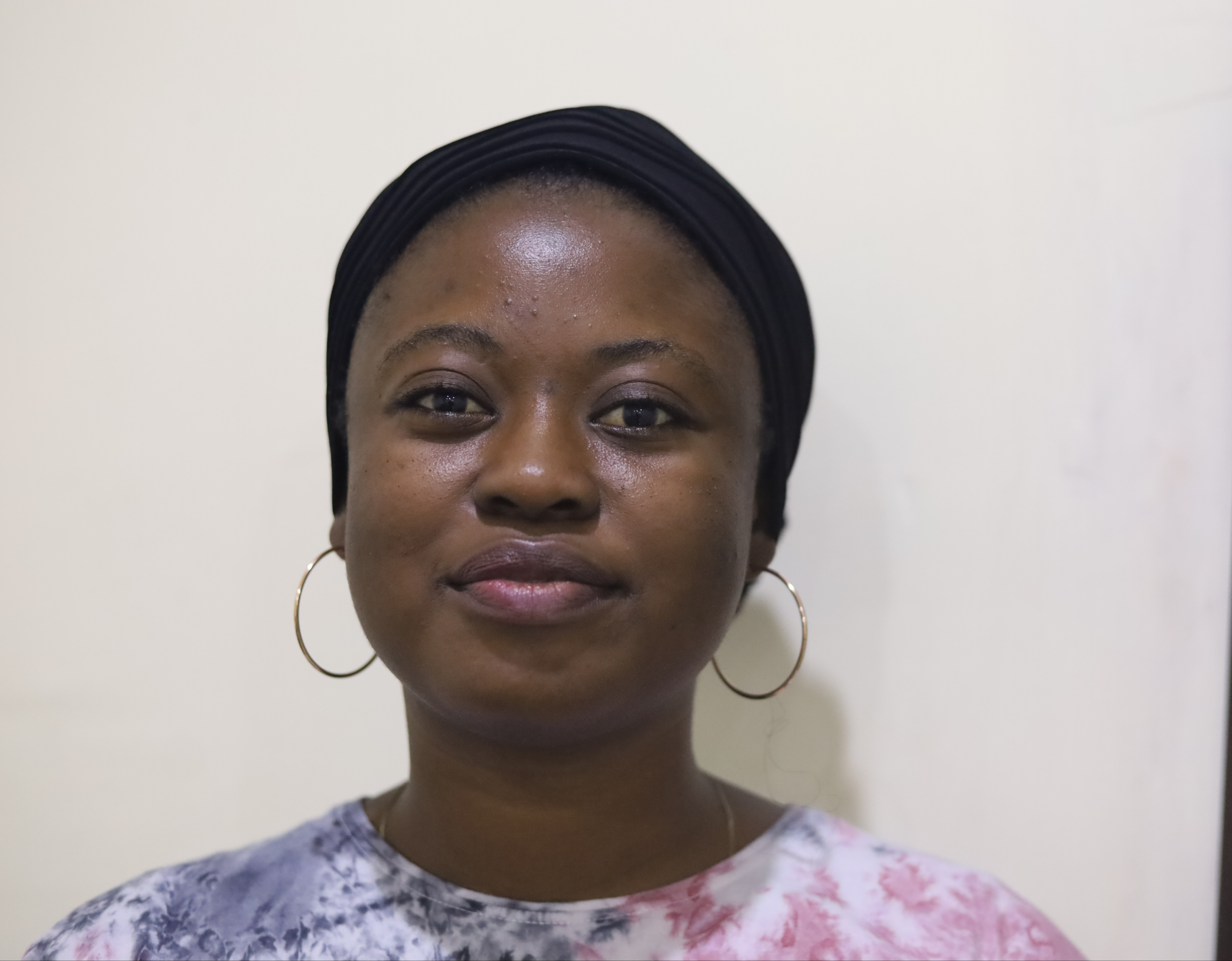 A woman with dark skin and dark hair wearing hoop earrings and red and blue shirt.