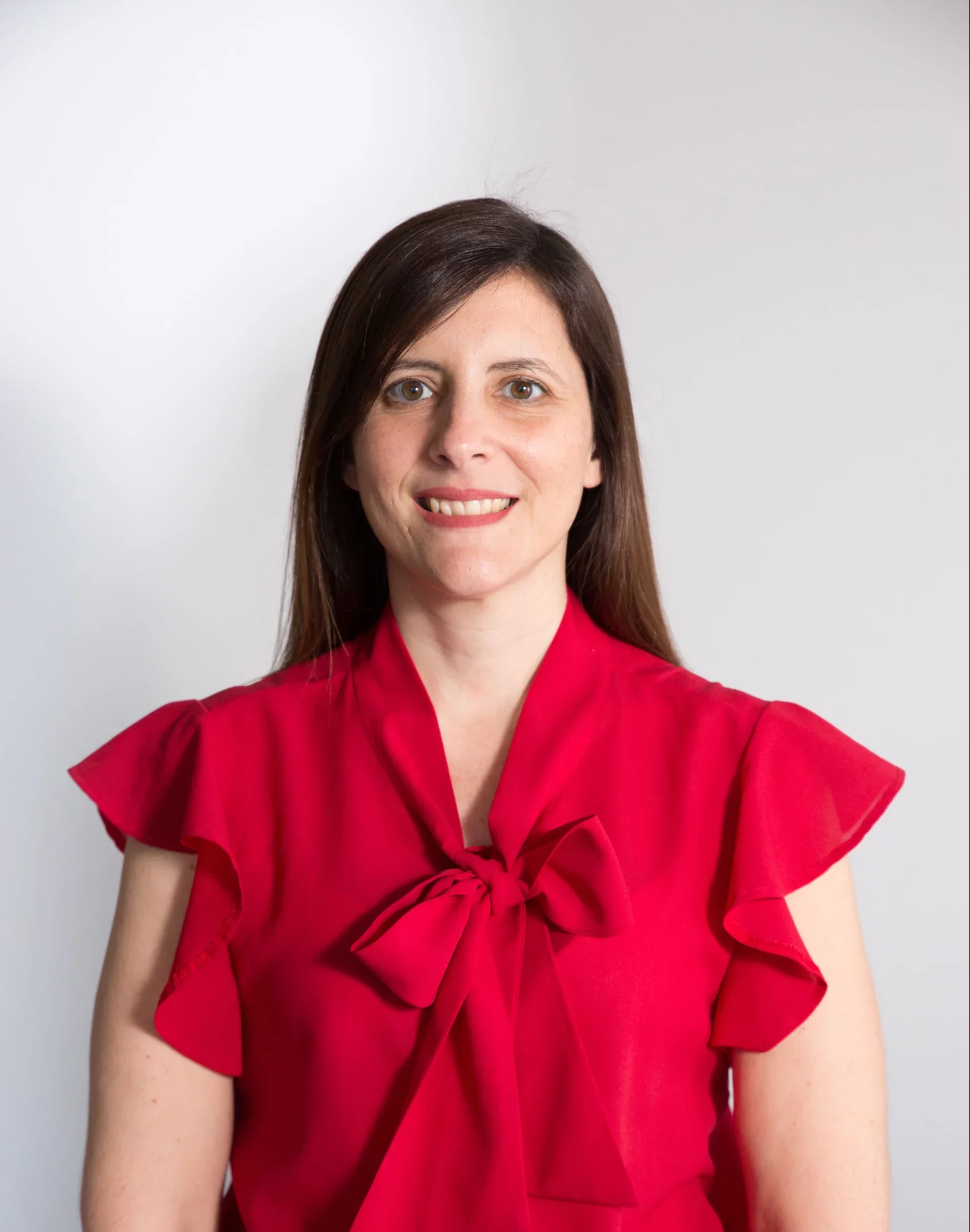 a woman with long dark straight hair wearing a bright red blouse