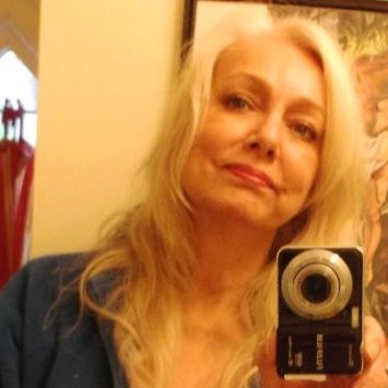 A woman with long blonde hair takes a mirror selfie with a black camera