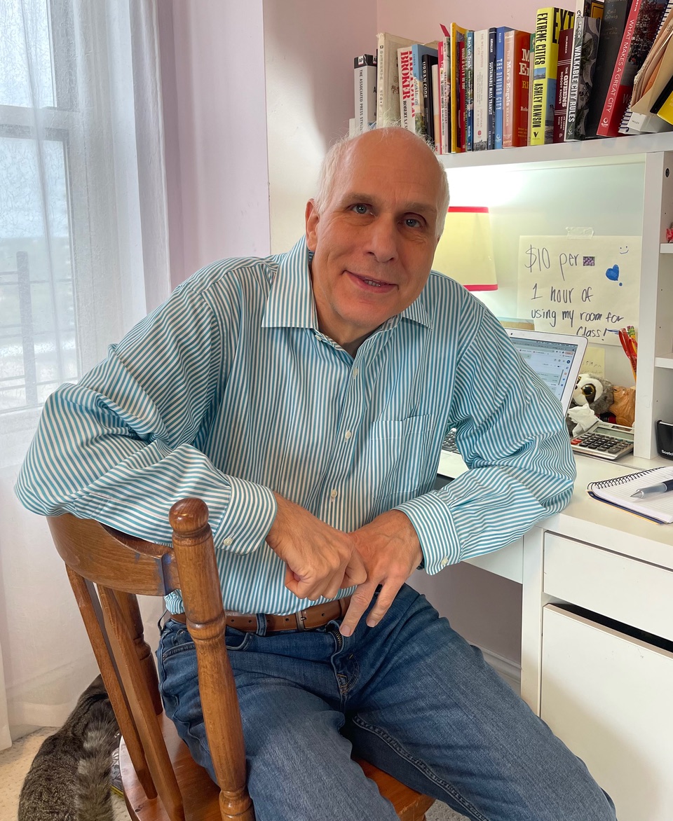 a man wearing a blue striped button down sitting at a desk