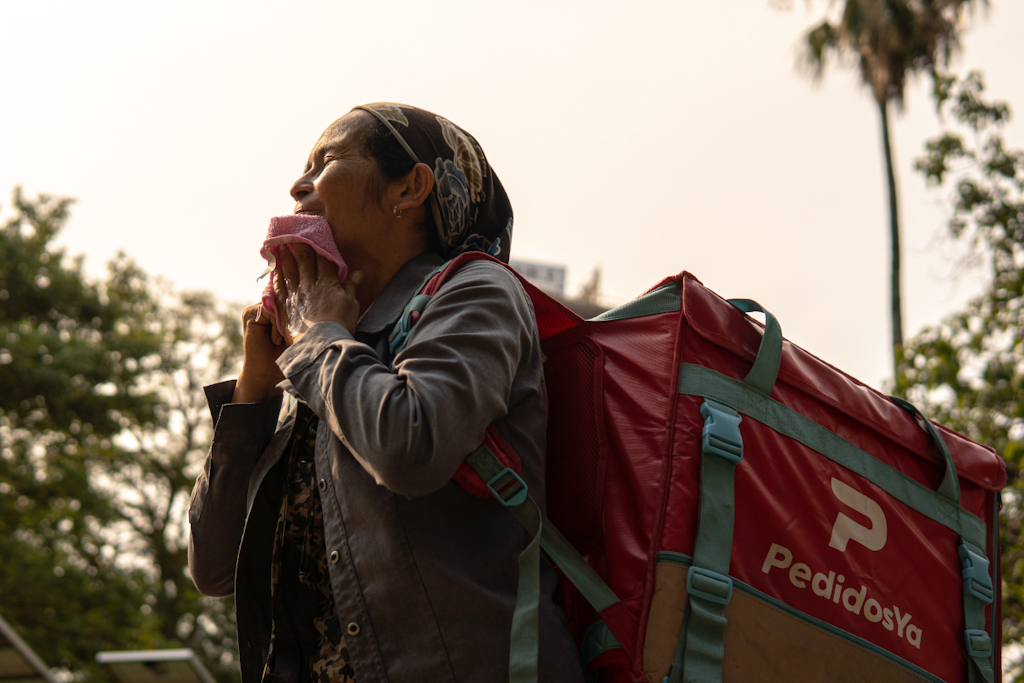 A woman carries a food delivery backpack in the heat