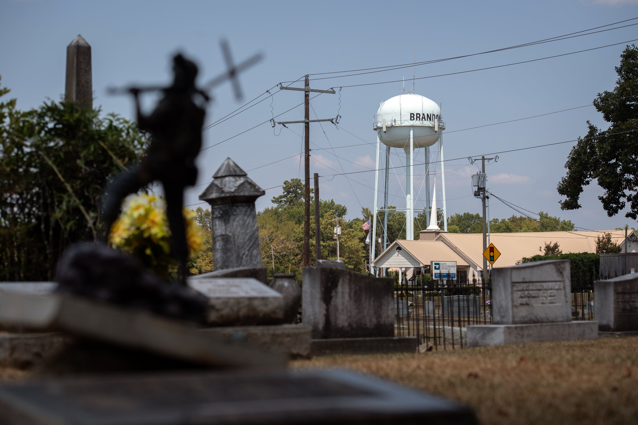 A scene in a small town with a cemetery in the foreground and a church and water tower in the background
