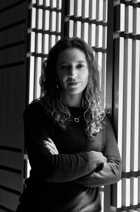 Black and white headshot of a woman with long curly hair with her arms folded