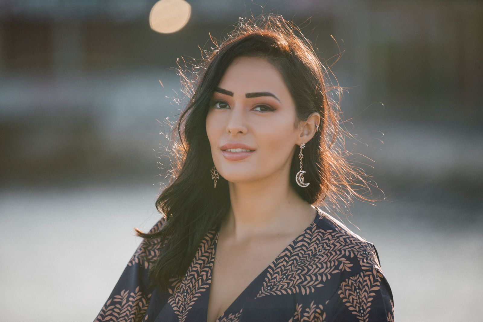 A woman with long dark hair wearing drop earrings and a black blouse