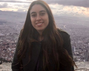 Isbale smiles at the camera against a stunning view of a city.