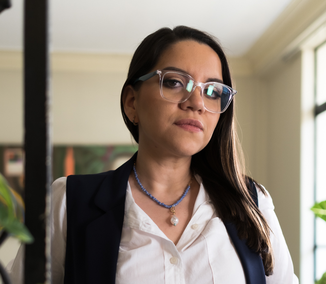 Thalíe Ponce wears glasses and a white button down shirt