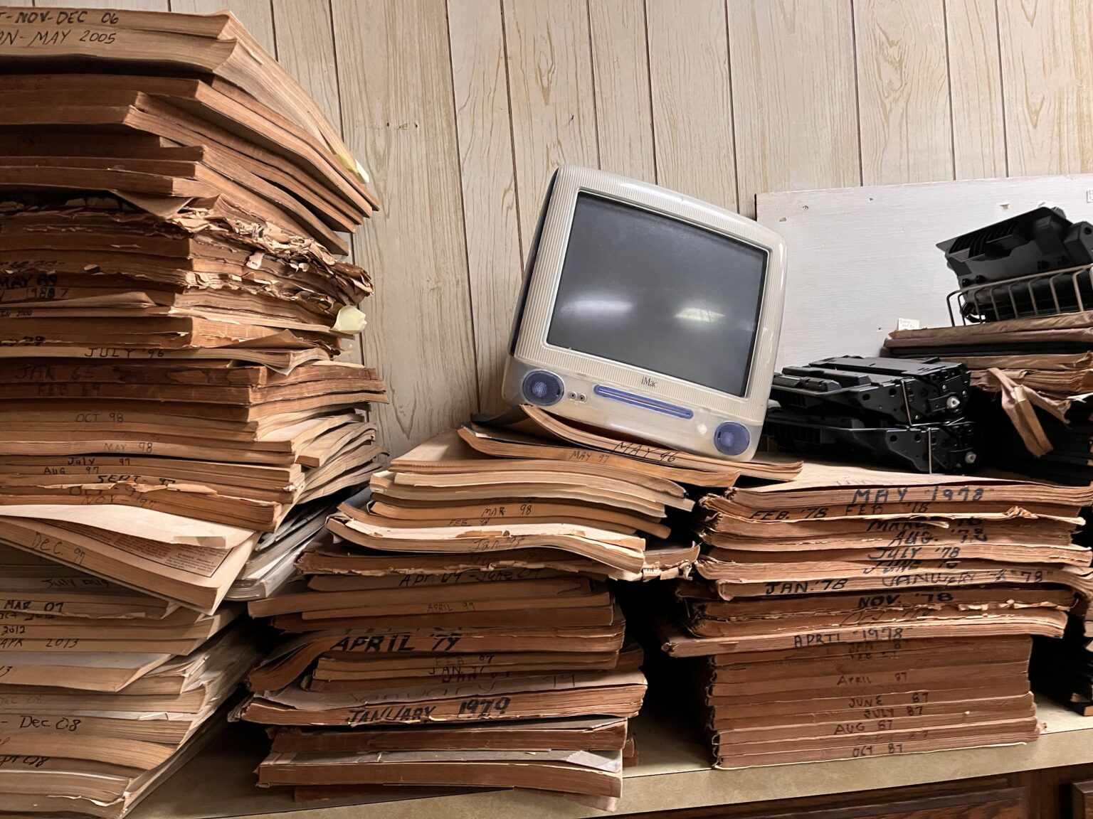 An old iMac sits atop newspapers.