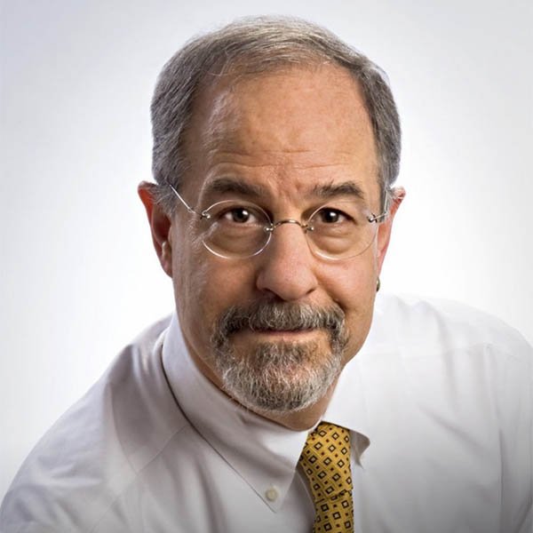 Headshot of Ted wearing glasses and a white collared shirt with a yellow tie