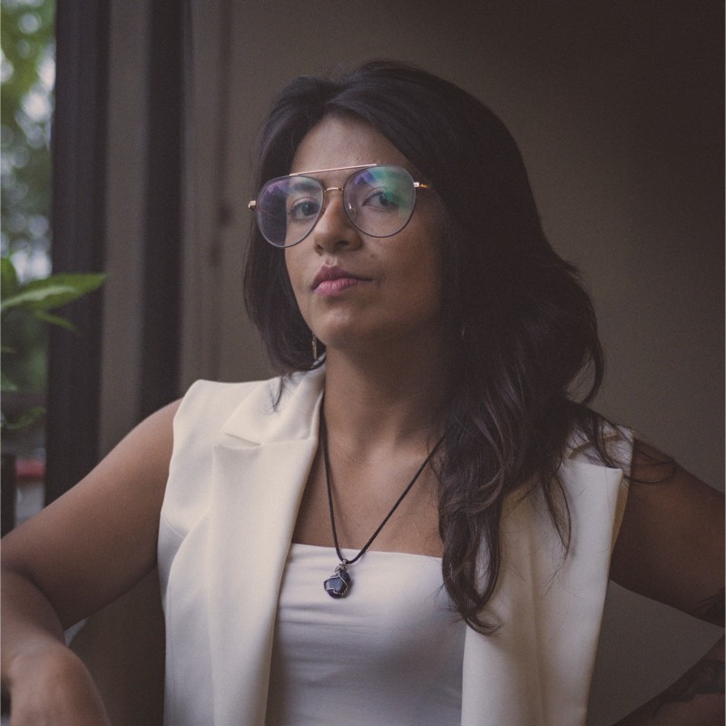 Headshot of Jessica wearing glasses and a white vest
