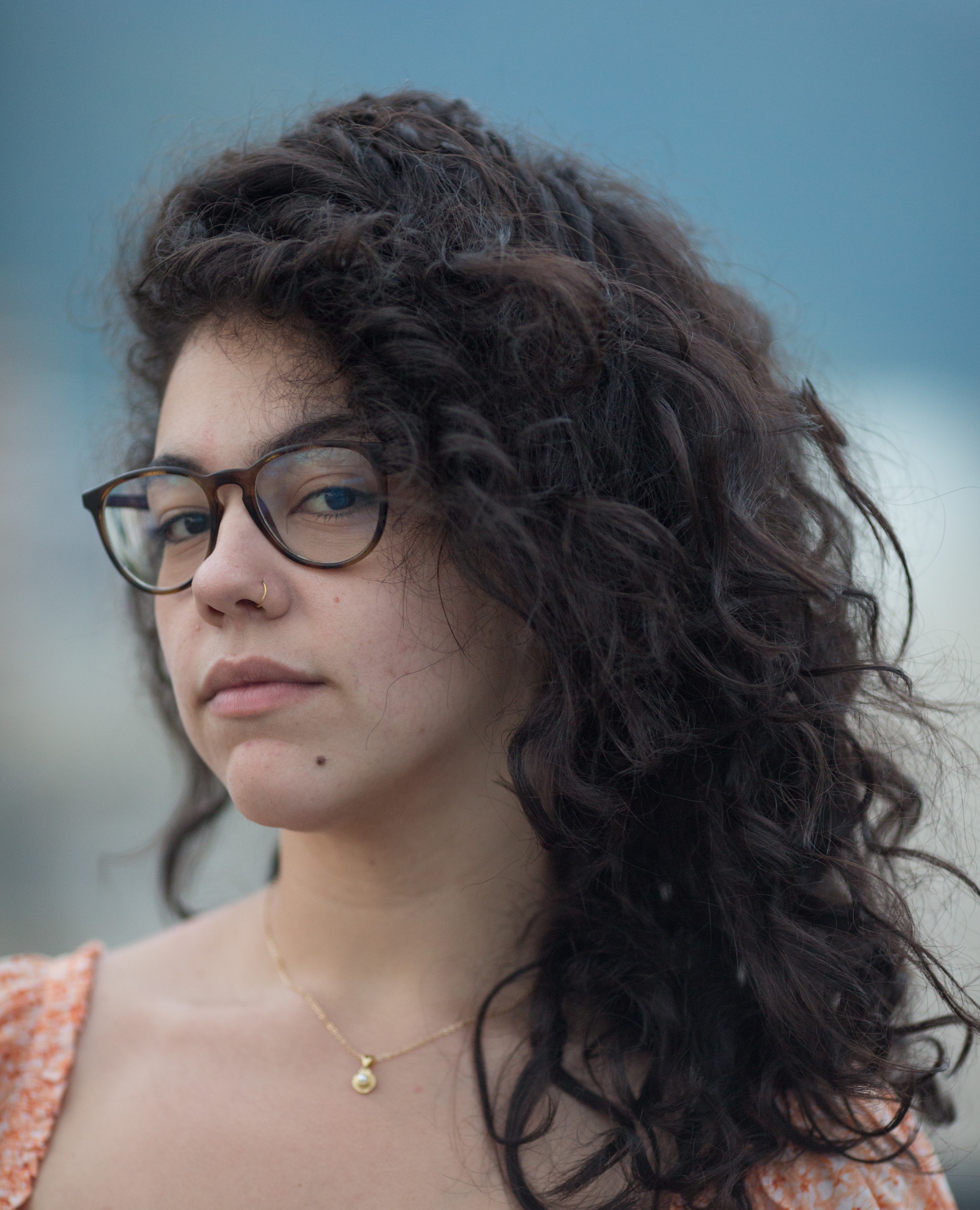 Headshot of Camille wearing glasses and an orange shirt