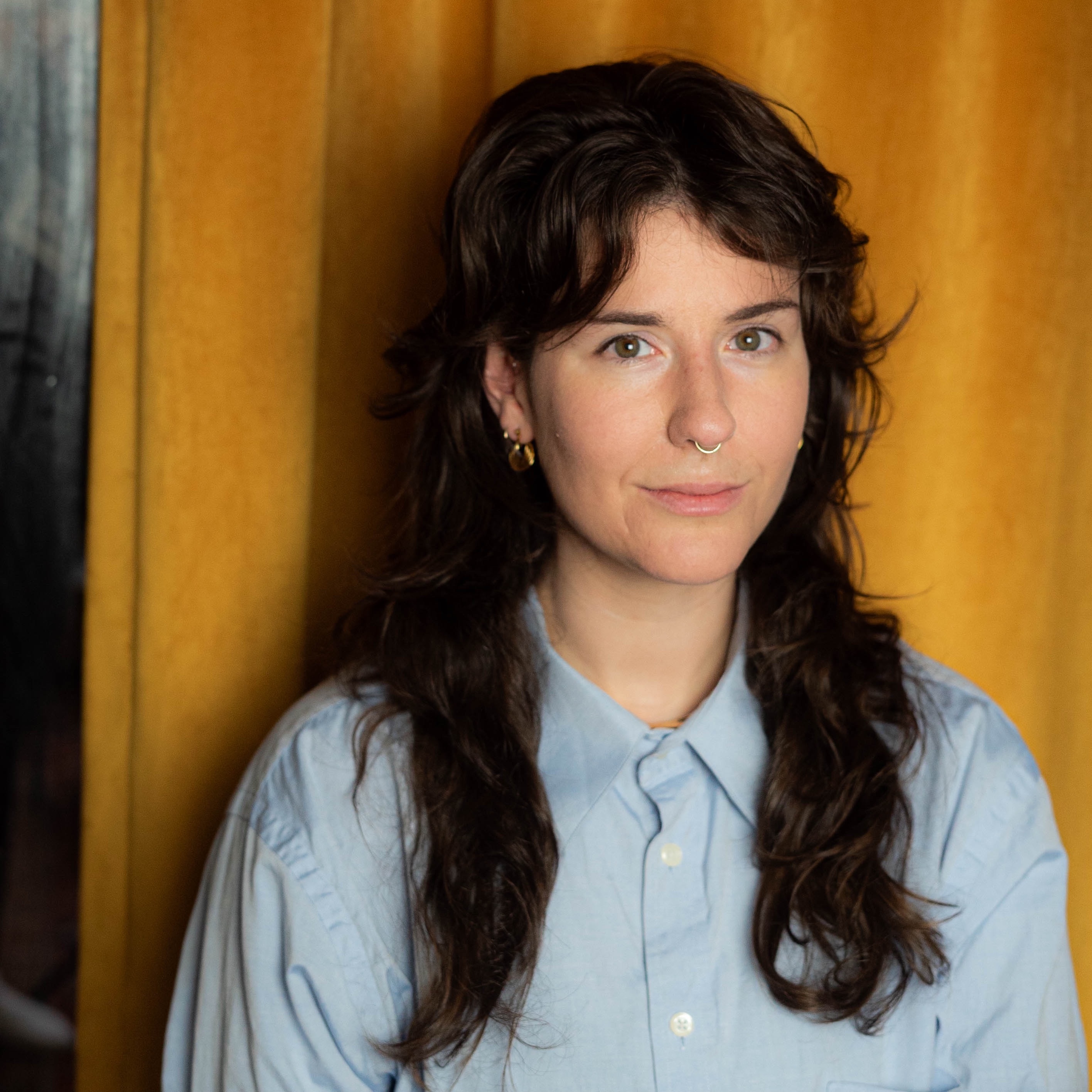 Molly wearing a blue button down against a yellow background
