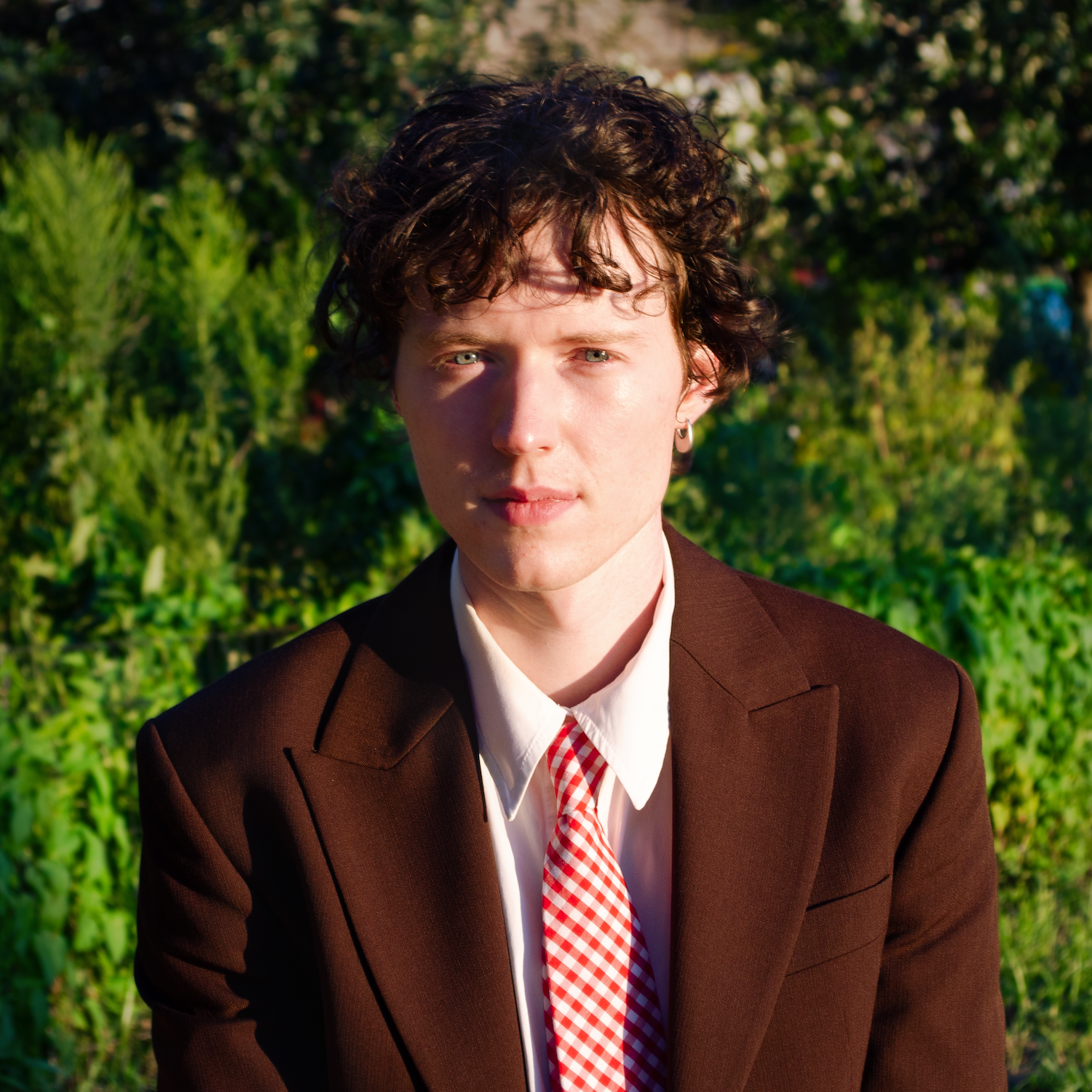 Headshot of person in brown jacket and red tie