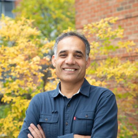 Man in blue shirt smiles with arms crossed