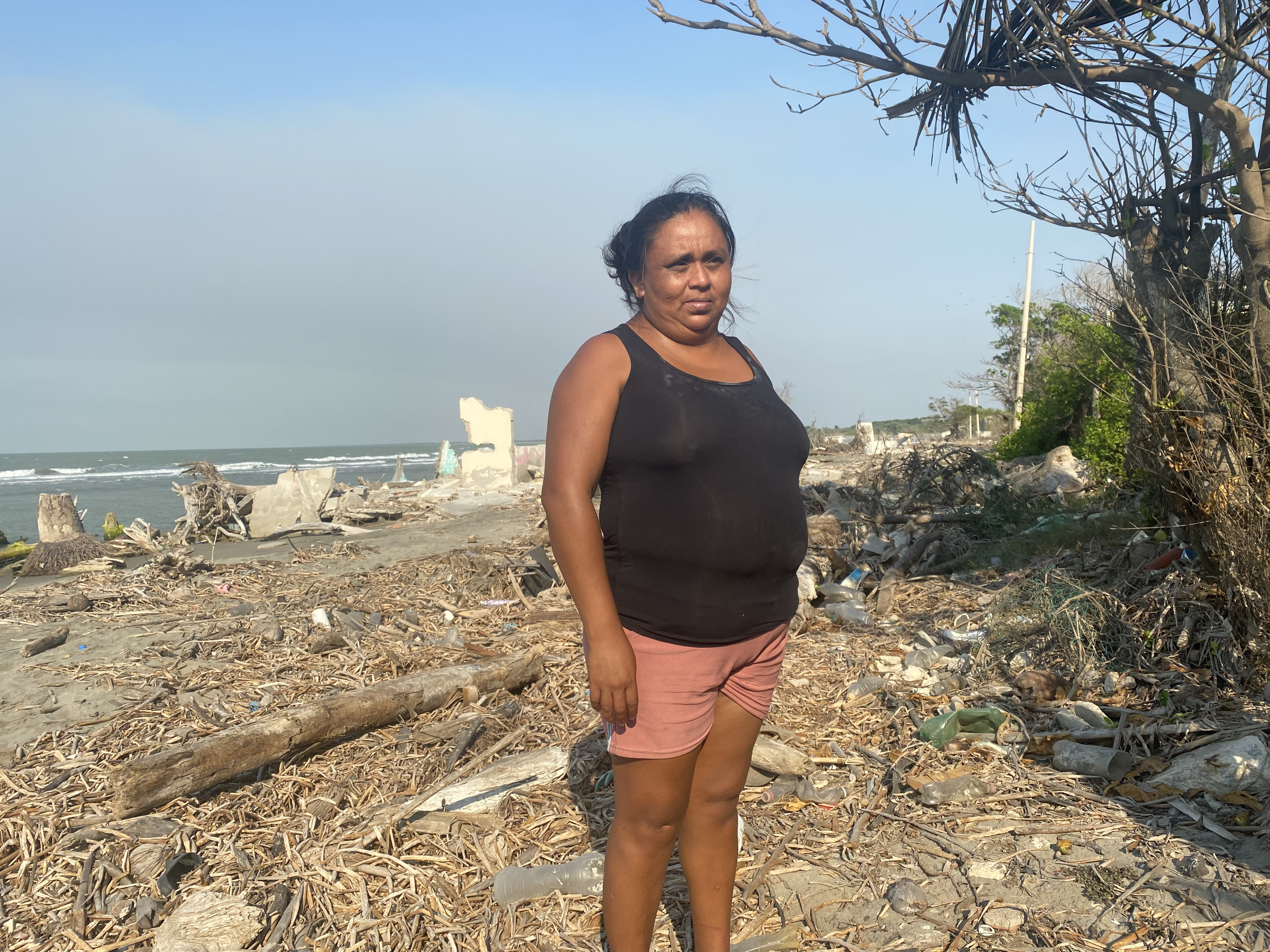 A woman in a black top stands in a beach area