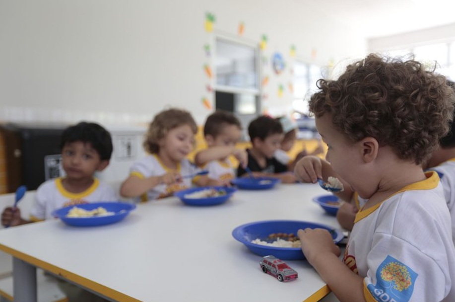 Small children eat around a table.