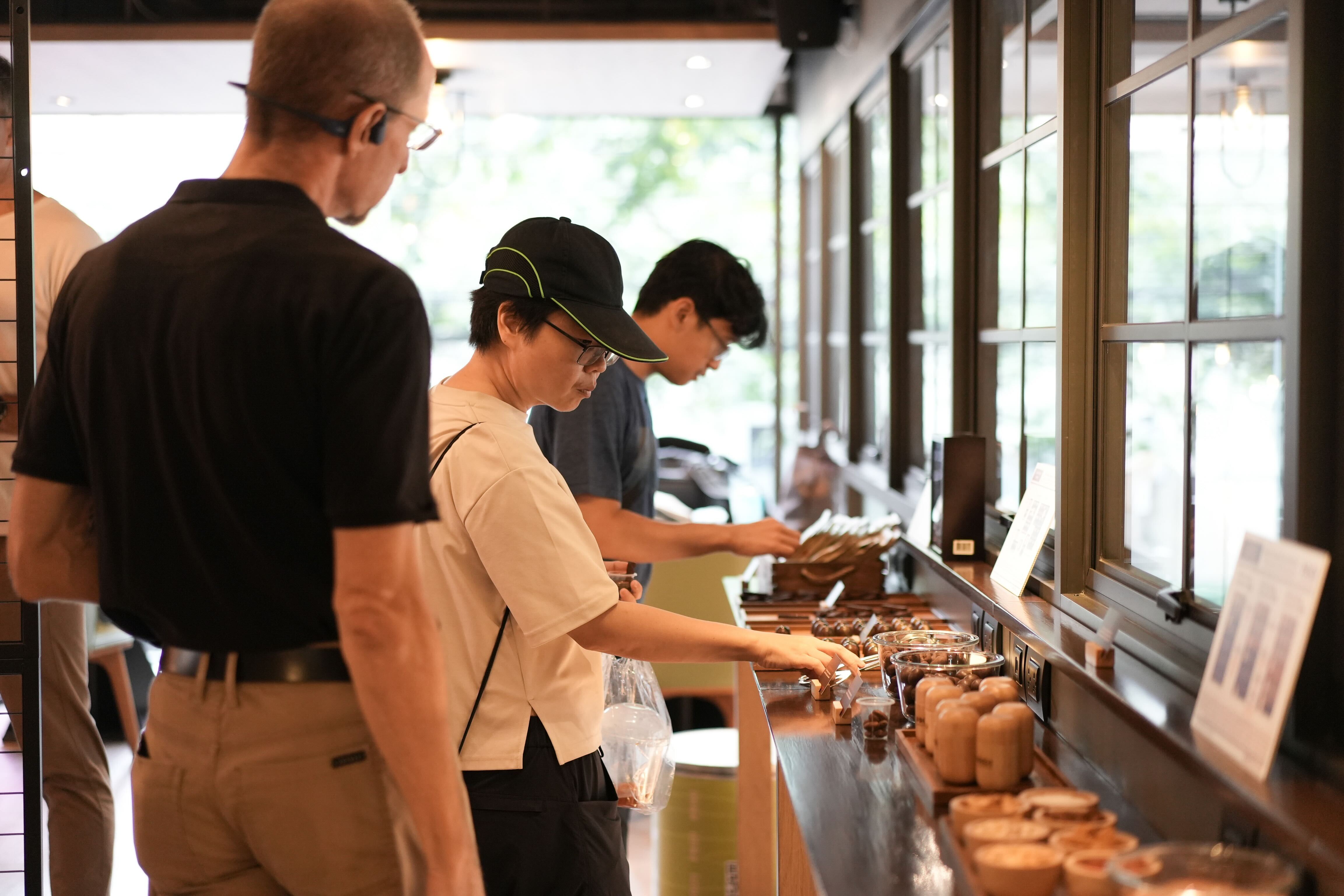 a line of people get food from a communal table