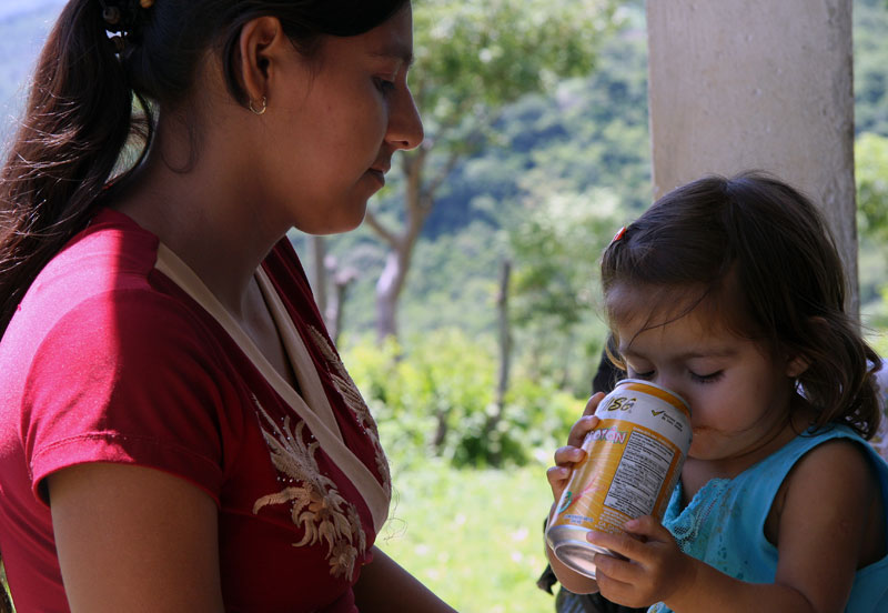 A local mother gives her child a sugary soft drink while waiting for researchers to assess her child's nutritional and cognitive levels. Image by Tracy Boyer. Honduras, 2009. Media file: 6a00d834520a2e69e2011571532845970b-800wi.jpg