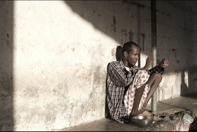 A mental hospital patient is chained to the post in Hargeisa, Somaliland. Many male patients suffer from the effects of chewing too much khat. Image by Narayan Mahon. Somaliland, 2009.